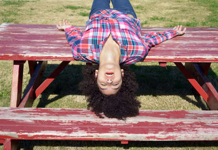 Teen girl laying upside down on picnic tableの写真素材
