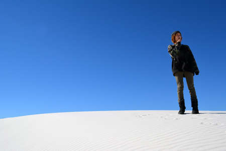 Teenager standing on sand dune hill, backed by a clear blue skyのeditorial素材