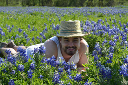 Young male farmer laying in a field of Texas bluebonnetsの写真素材