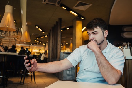 young businessman with a beard makes selfie in a beautiful and cozy restaurantの写真素材