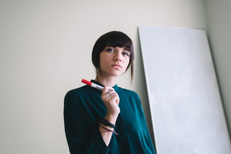 Young beautiful girl student with marker writing or drawing stands at the whiteboard.の写真素材