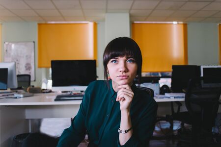 Worker young beautiful woman sitting in a modern office and looking at the camera.の写真素材