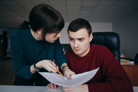 Young couple students to carefully look at the paper. Girl with glasses explaining something to the guy and the guy does not understand. Students are taught.の写真素材