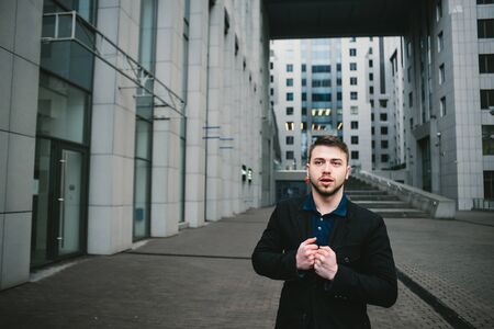 Outdoor portrait of a serious young businessman with a beard against the backdrop of beautiful modern architecture.の写真素材