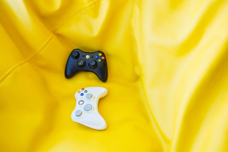White and black joystick for game console on a bright yellow background. Game concept.