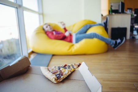 The last piece of pizza on a background of office space for recreation.の写真素材