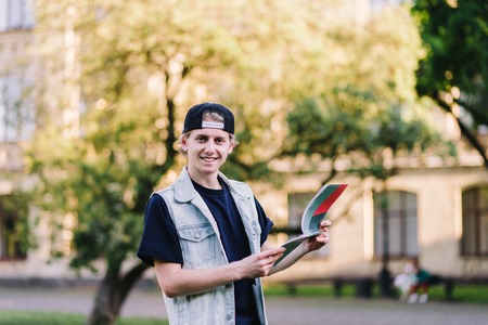 Positive stylish student reading a notebook on the background of the university. A teenager on the background of a college campus. Student Life.の写真素材