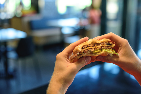 Berger in the hands of a young man. Fast food.の写真素材