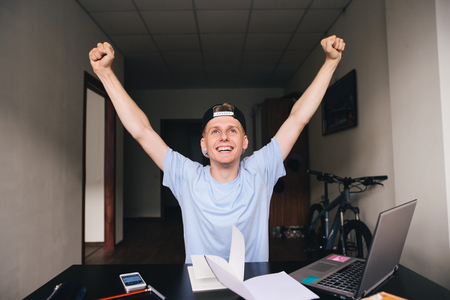 The student is happy because he has fulfilled all the tasks. Teenager raised his hands upの写真素材
