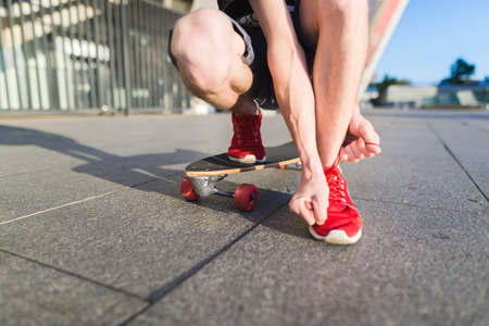 A man skater in red sneakers resorts from the ground riding on a longboard. Street concept.の写真素材