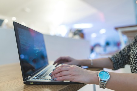 Business woman's hands print on a laptop keyboard in a cafe