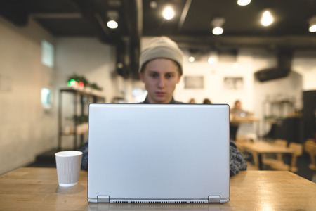 The freelancer works for a laptop in a cozy cafe. A student uses a laptop in a cafe. Focus on the laptop.の写真素材
