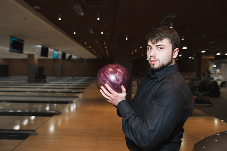 Portrait of a business man with a bowling ball in his hands during the game. Rest in a bowling gameの写真素材