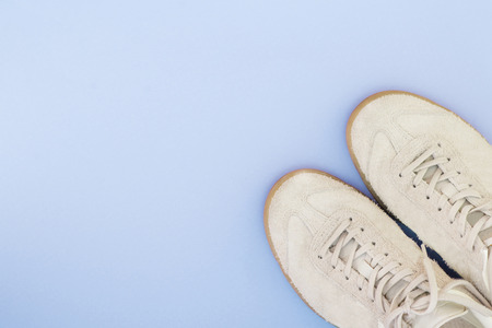 Light sneakers on a bright blue background. Minimalistic composition with sneakers and spotted text. Flat lay.の写真素材