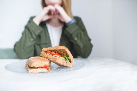 The appetizing sandwiches lie on the table in a plate on the background of a woman. The woman dishes with sandwiches.の写真素材
