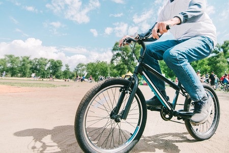 A man rides a mountain bike on a sunny summer day. Hipster rides a bike in the park.