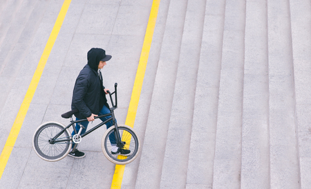 A stylish young man climbs a ladder with BMX by bicycle in his hands. Walk with a bike. BMX concept.の写真素材