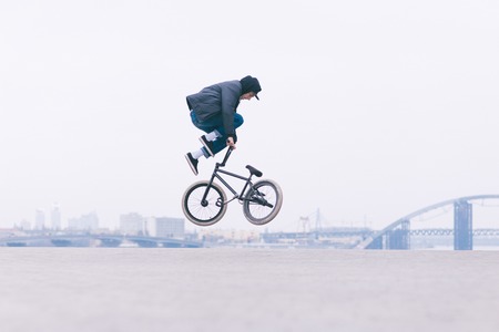 Young BMX bicycle reader does tricks in the air against the background of the urban landscape. BMX freestyle.の写真素材