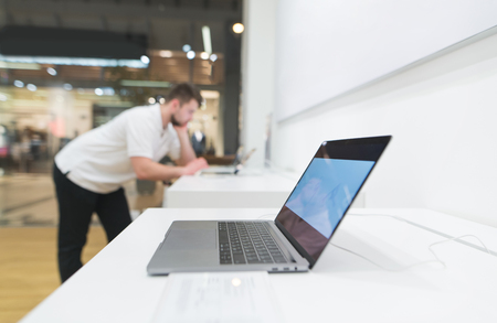 Laptop is in the shop window of electronics on the back of the buyer. Buy a laptop in a technology store. Focus on the laptop.の写真素材