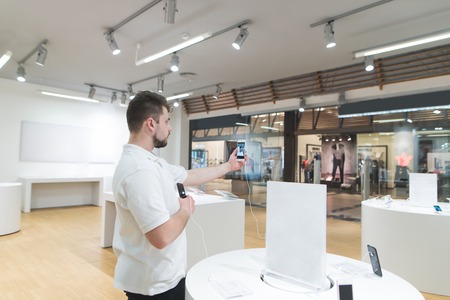 Buyer makes a sephi on a smartphone in the electronics store. tests the front camera when choosing a smartphone. The buyer selects a smartphone in the technology store.の写真素材