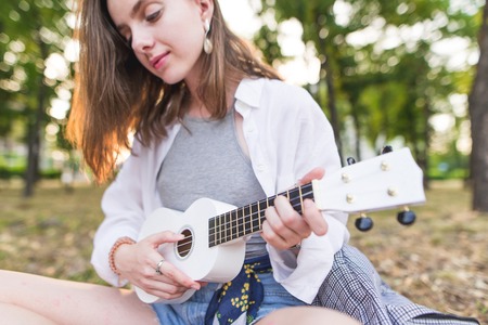 Closeup portrait of a girl with a ukulele hands outdoors. Musical Kotznapt. Playing Ukulele. Musical concept. Hawaiian guitar.の写真素材