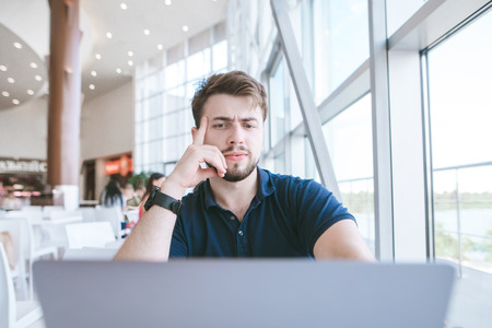 Attractive man with a beard of sydt in a cafe and focused on the screen of a laptop. Businessman in...