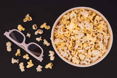 Flat lay. Copyspace. Cinema Concept. Background. Popcorn, cup and 3d glasses on a black background. Focus on 3d eyepiecesの写真素材