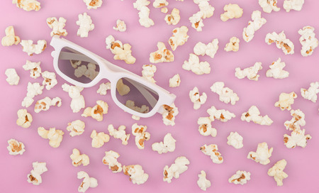 Background. Popcorn on a pastel pink background. 3d glasses for watching a movie, top view. Copyspace. Cinema Concept.の写真素材