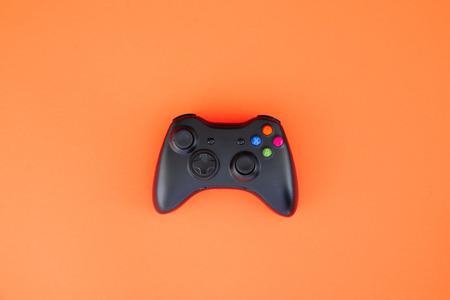Black gamepad, controller on a red background. Computer game competition. Gaming concept. Wireless...