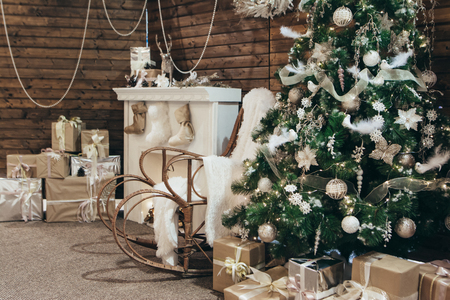 Decor of the Christmas photo zone: a Christmas tree, rocking chair, fireplace and many gifts. Cozy New Years photo zone. Christmas conceptの写真素材