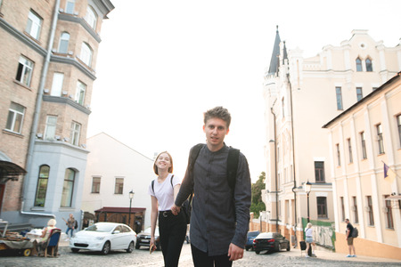 Young couple walks along the town street holding hands, girl follows a young man. Beautiful happy couple walking around the town. Follow me.の写真素材