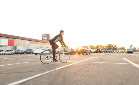 Rider in a cap and dark sportswear rides around the city on a white highway, on the background of the sunset.Background. Transport and people.の写真素材