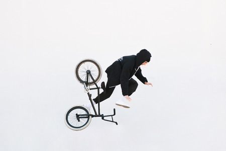 The Bmx rider falls into the dark background with a white background. Bmx and a cyclist are flying...