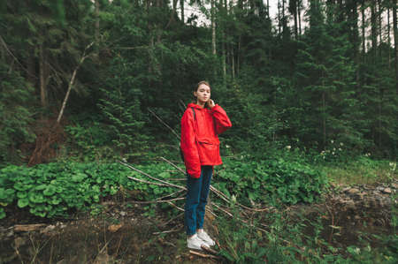 Tourist girl standing on a tree trunk over the mountain river, looking at the camera, feeling calm...