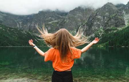 Hipster girl with her hair stands on the background of Lake Morskie Oko and poses for the cameraの写真素材
