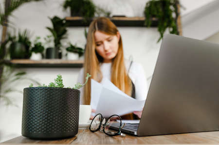 Abstract photo with selected focus. Cute girl sitting in cafe with laptop and business papers in her...