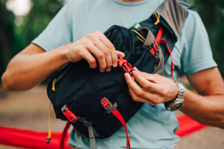 Close photo of male tourist fastens fastex on waist bag. A man carries a waist bag on his shoulder. Equipment for tourism.の写真素材