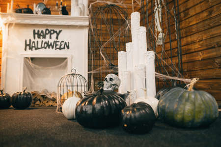 Pumpkins with a skull on a background of candles and a fireplace with the inscription "Happy Halloween". Decorated interior for Halloween.の写真素材