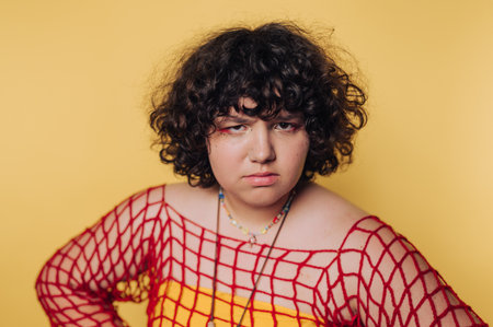 Portrait of an individual wearing a colorful outfit with curly hair posed against a bright yellow backgroundの写真素材