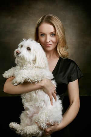 Beautiful blonde woman with a cute dog. Professional portrait in a photo studio.