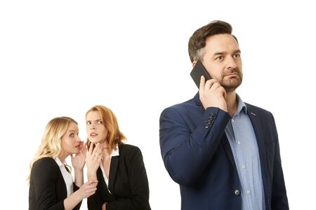 Man is phoning while two businesswomen are whispering a secretの写真素材