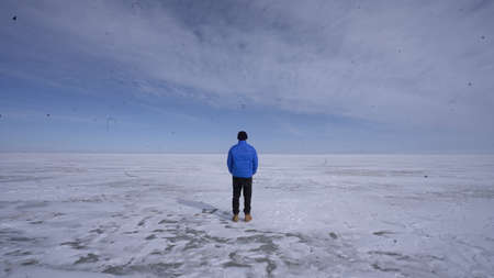 A man in a blue jacket walks along the frozen lake. A man walks along the frozen lake.の写真素材