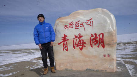 A man standing in front of a stone sculpture in the snowの写真素材