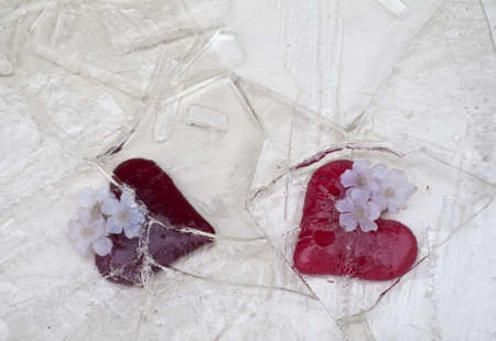 Two red glass hearts covered by broken iceの写真素材