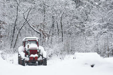 Red and green tractor in the snow covered forestの写真素材