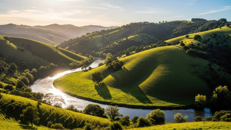 An aerial view showcases a landscape of rolling hills covered in lush green vegetation. A meandering river flows through the scene, reflecting the natural light. The photograph uses a natural composition and captures the landscape's textures and colors. This image is suitable for various commercial uses, including advertising and editorial content.の素材