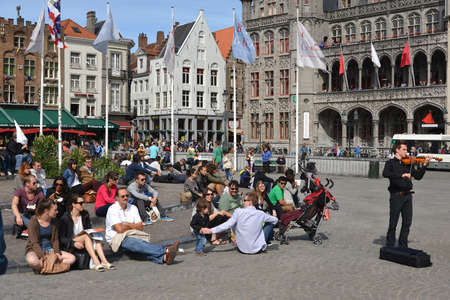 People relax and listen to the musician on a square in Brussels.のeditorial素材