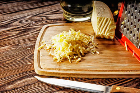Grated shredded fresh cheese on a cutting Boardの写真素材