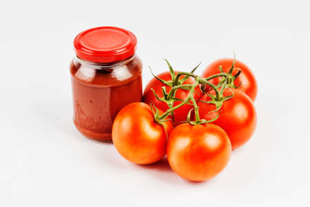 Tomato paste in a jar and tomatoes on white backgroundの写真素材
