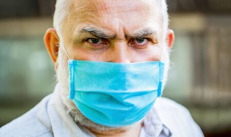 Portrait of an old man, years old, in a medical mask. Concept danger of coronavirus for the elderly. Coronavirus, illness, infection, quarantine, medical mask. Old man wearing face mask. Closeupの写真素材